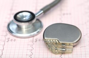 Pacemaker and stethoscope on heart monitor sheets